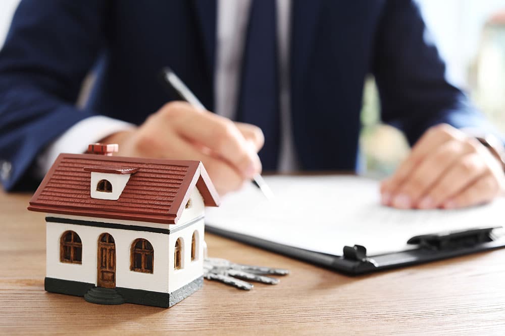 House model and blurred real estate agent on background, closeup