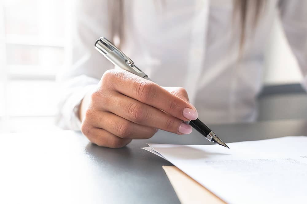 Business woman signing contract document on office desk, making a deal.