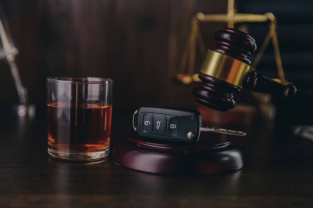 Drinking and driving concept. Car key on a wooden table, pub background