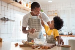 African Father and son baking cookies at home together.