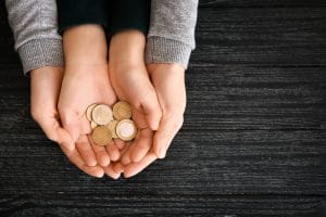 Hands of woman and his son holding coins on wooden table. Concept of child support