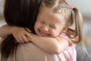 Funny little child girl smiling embrace foster care parent mum, adorable sweet small kid adopted daughter cute face hug mother caretaker holding tight feel happy express love get new family concept