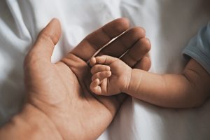 Close-up small hands of baby is lying in men of his father hands, concept of caring, fatherhood, family