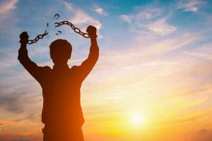 Silhouette image of a businessman with broken chains in sunset