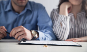 Couple with divorce contract and ring on desk. Divorce