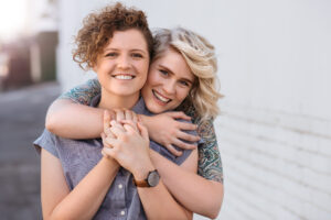 Portrait of a smiling young lesbian couple hugging each other while standing together on a city street
