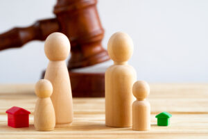 Divorse property division concept. Wooden family with house and judge gavel close up